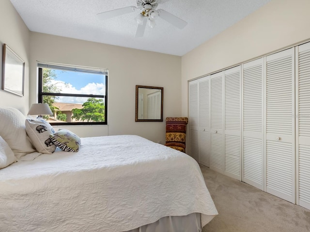 bedroom featuring a closet, a textured ceiling, light colored carpet, and ceiling fan