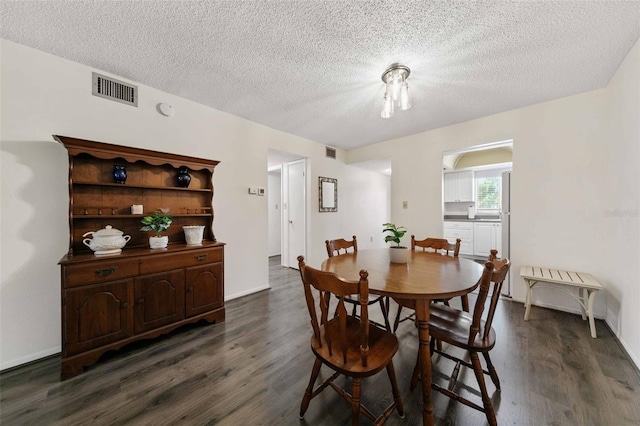 dining area with a textured ceiling and dark wood-type flooring