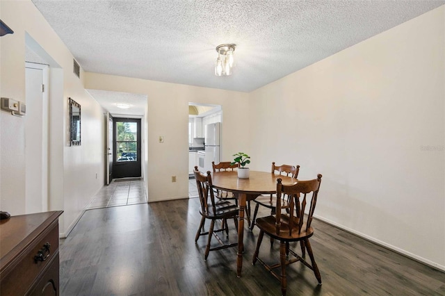 dining area featuring wood-type flooring and a textured ceiling