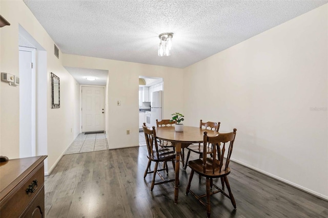 dining room featuring wood-type flooring and a textured ceiling