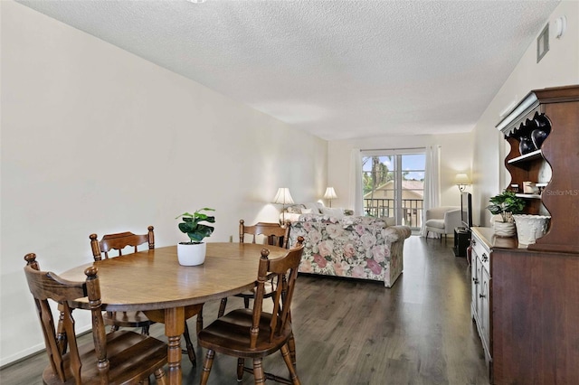 dining space with a textured ceiling and dark wood-type flooring