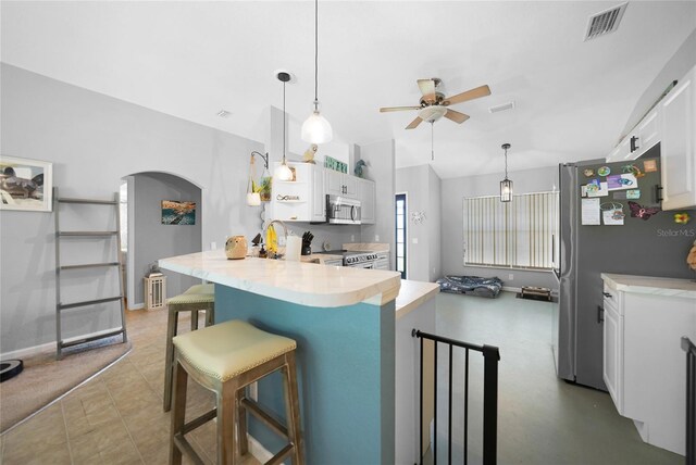 kitchen with white cabinets, kitchen peninsula, stainless steel appliances, and a breakfast bar area