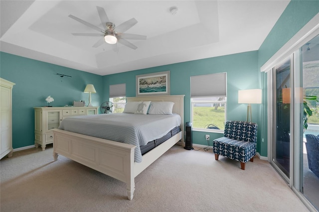 carpeted bedroom with access to outside, a tray ceiling, and ceiling fan