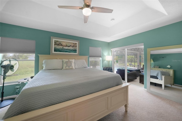 bedroom with a raised ceiling, ceiling fan, light colored carpet, and access to outside