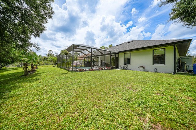 rear view of property featuring a lanai and a lawn