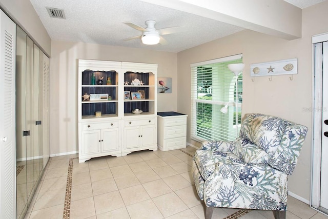 living area featuring a textured ceiling, ceiling fan, and light tile patterned floors