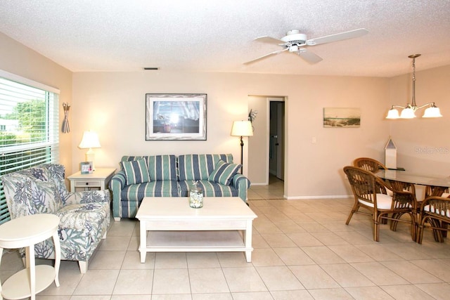 living room with a textured ceiling, ceiling fan with notable chandelier, and light tile patterned flooring