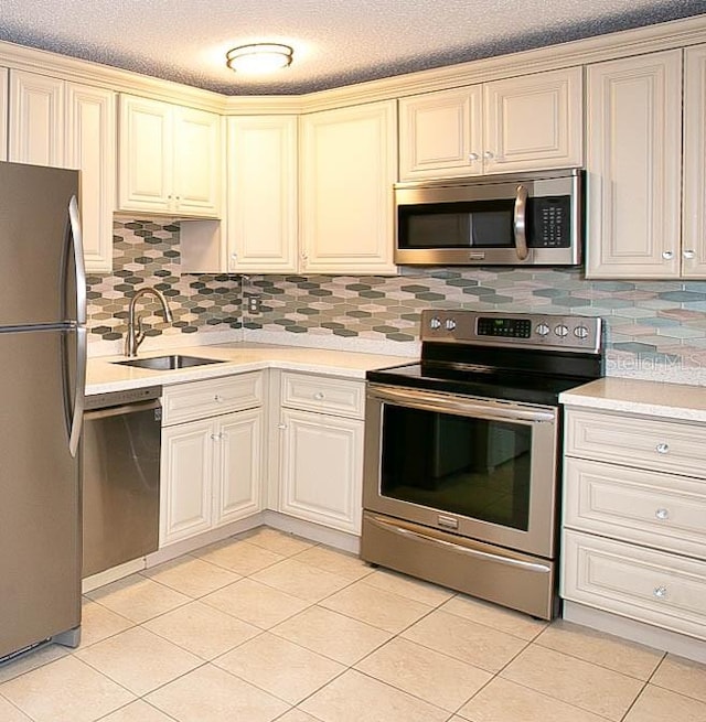 kitchen featuring appliances with stainless steel finishes, decorative backsplash, sink, cream cabinetry, and light tile patterned floors