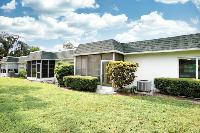 back of property with a lawn, a sunroom, and central air condition unit