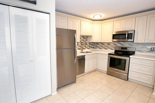 kitchen with sink, decorative backsplash, light tile patterned flooring, and stainless steel appliances