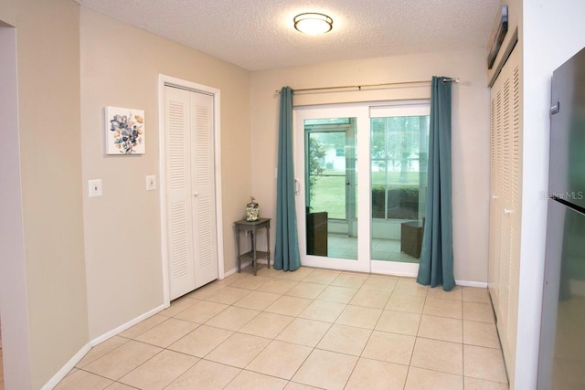 spare room with a textured ceiling and light tile patterned floors