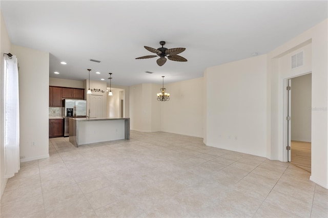 unfurnished living room featuring light tile patterned flooring and ceiling fan with notable chandelier