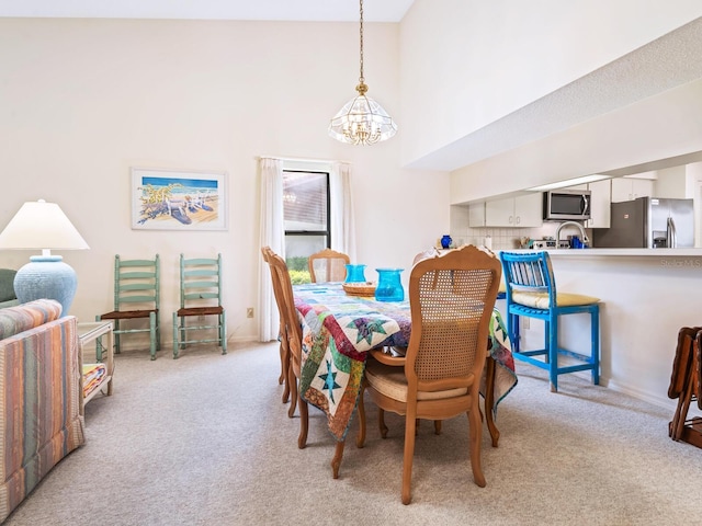 dining space featuring light carpet, high vaulted ceiling, and an inviting chandelier