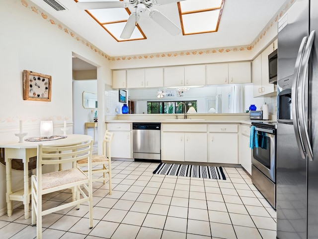 kitchen featuring stainless steel appliances, light tile patterned flooring, sink, ceiling fan, and white cabinets