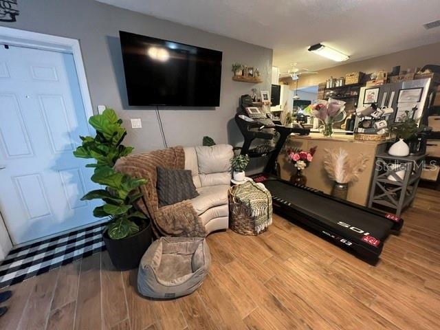 living room featuring visible vents, a ceiling fan, and wood finished floors