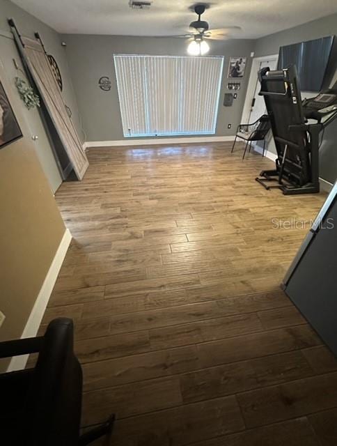 interior space featuring wood finished floors, a ceiling fan, and baseboards