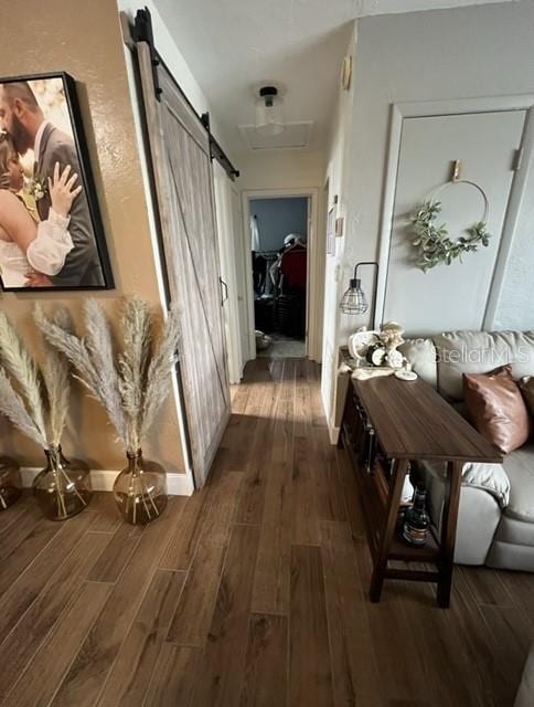 hall with a barn door and wood finished floors