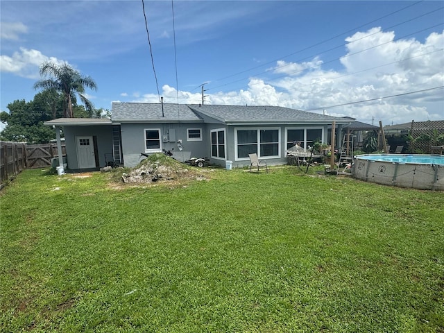 rear view of house with fence private yard, a lawn, a fenced in pool, and stucco siding