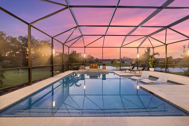 pool at dusk with glass enclosure, a patio area, and a water view