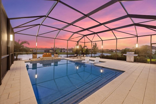 pool at dusk with glass enclosure, a grill, a water view, and a patio