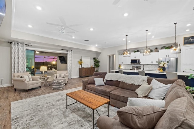 living room featuring ceiling fan, light hardwood / wood-style flooring, and crown molding