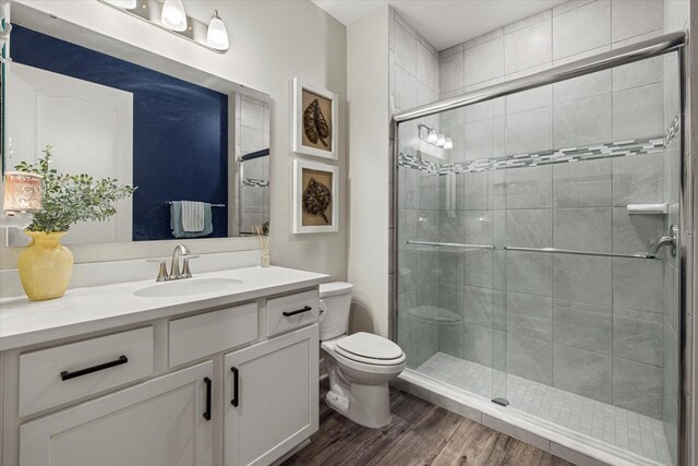 bathroom featuring walk in shower, hardwood / wood-style floors, vanity, and toilet