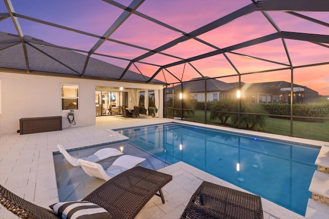 pool at dusk with a patio area and a lanai