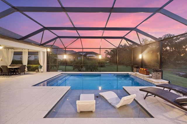 pool at dusk featuring a lanai and a patio