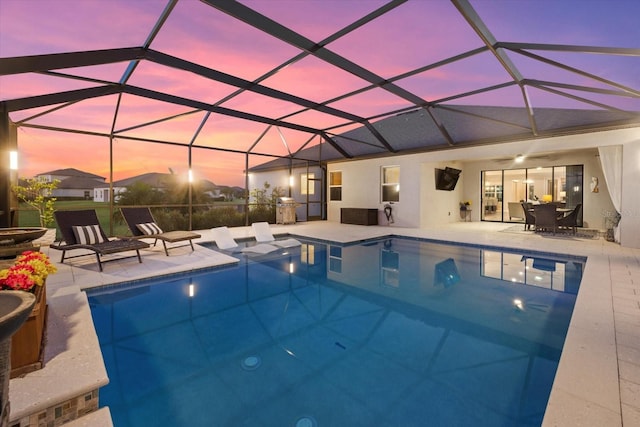 view of pool with a patio, glass enclosure, and ceiling fan