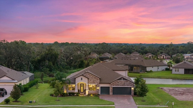 view of front facade featuring a yard, a water view, and a garage