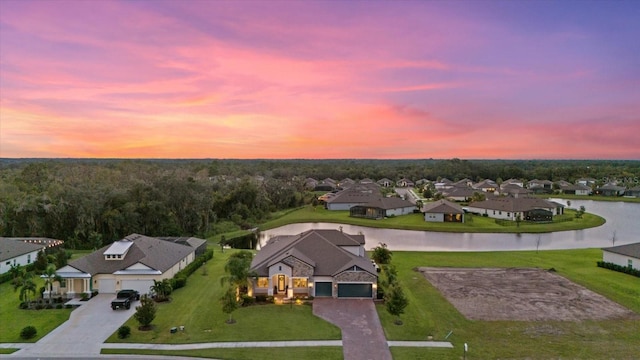 aerial view at dusk featuring a water view