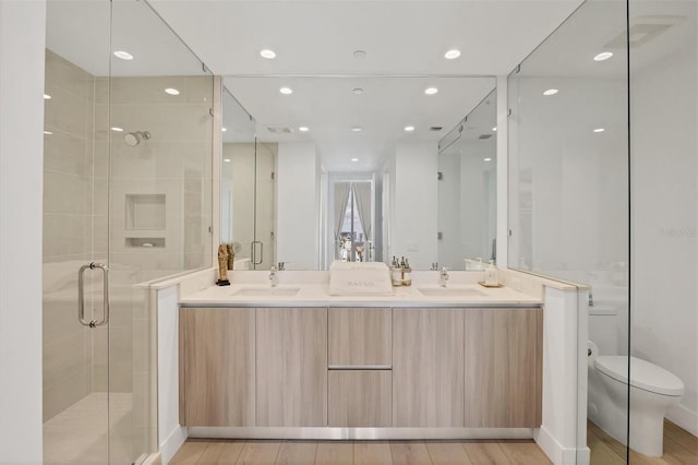 bathroom featuring toilet, vanity, an enclosed shower, and hardwood / wood-style flooring