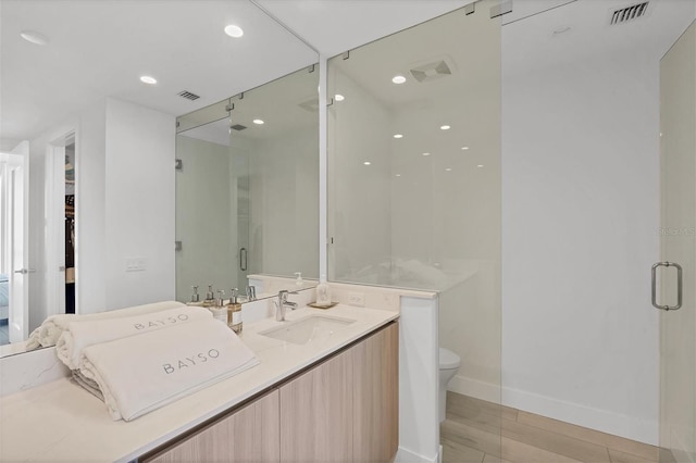 bathroom featuring a shower with door, vanity, wood-type flooring, and toilet