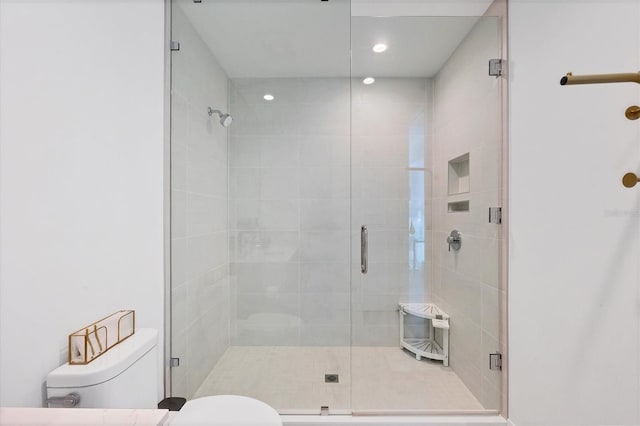 bathroom featuring a shower with shower door and toilet