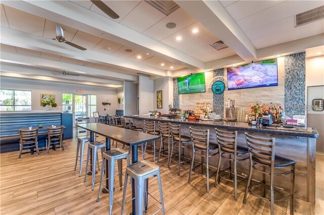 bar featuring ceiling fan, beam ceiling, and dark stone countertops