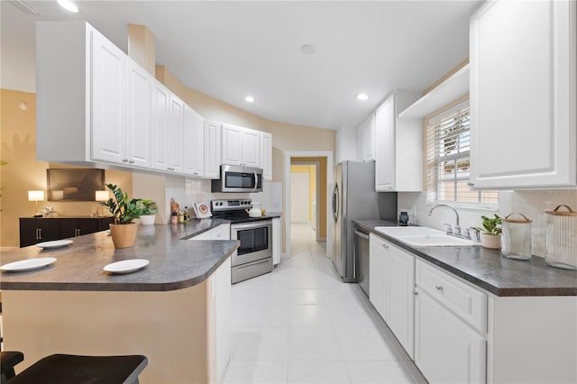 kitchen featuring a breakfast bar, kitchen peninsula, sink, appliances with stainless steel finishes, and white cabinets