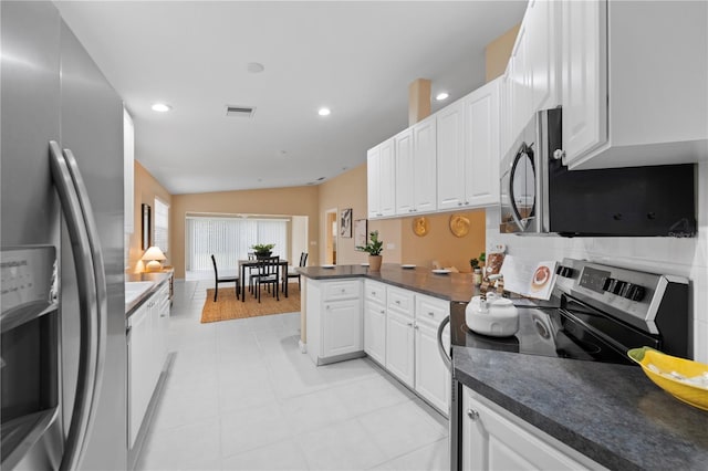 kitchen with vaulted ceiling, kitchen peninsula, stainless steel appliances, and white cabinetry