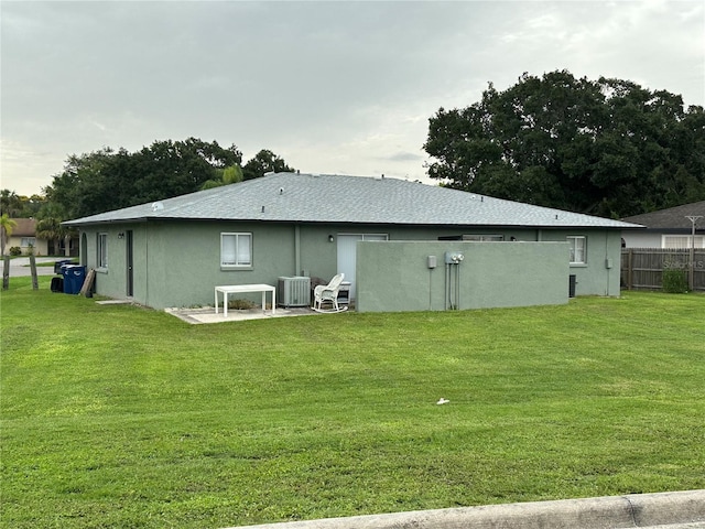 rear view of house featuring a lawn, central AC, and a patio area