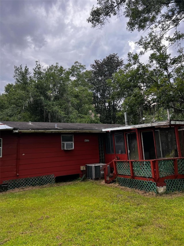 back of property with a sunroom, central AC unit, and a yard