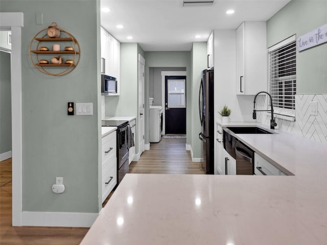 kitchen featuring refrigerator, sink, light wood-type flooring, white cabinets, and black electric range oven