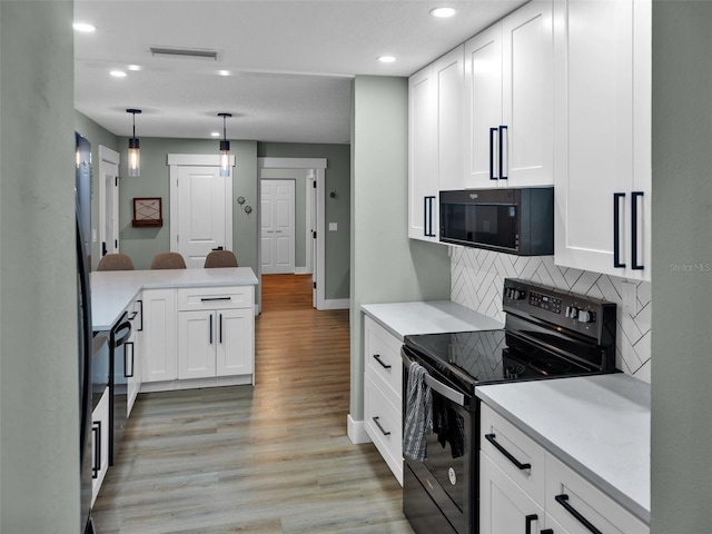 kitchen with white cabinetry, backsplash, black appliances, and light hardwood / wood-style floors