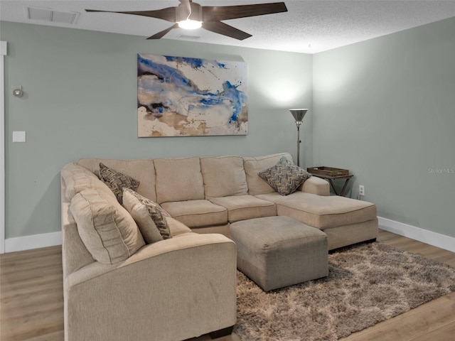 living room featuring ceiling fan, light hardwood / wood-style flooring, and a textured ceiling