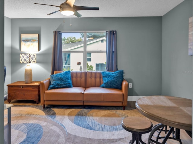 living room featuring ceiling fan and a textured ceiling