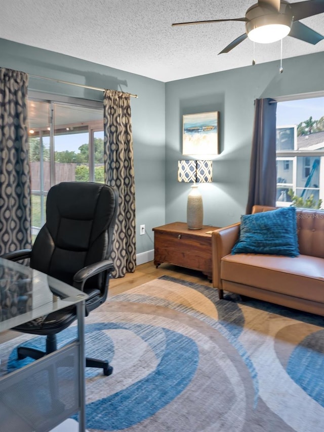 office space with a textured ceiling, ceiling fan, and light wood-type flooring