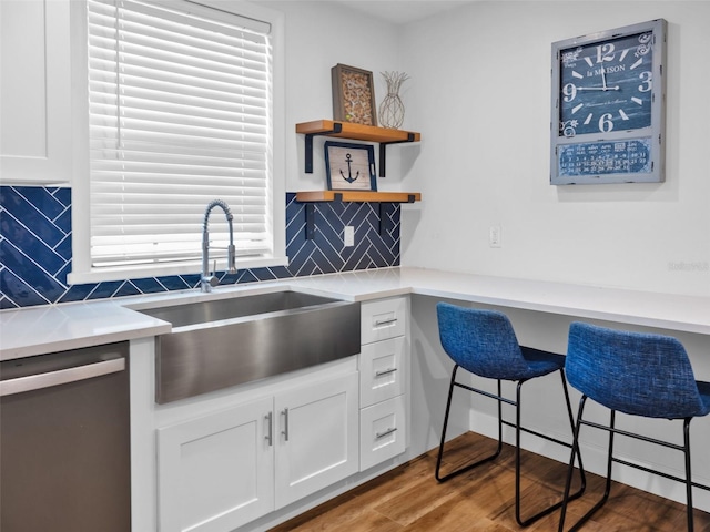 kitchen with backsplash, dishwasher, white cabinets, and sink