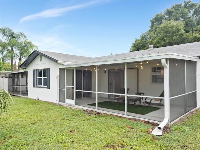 rear view of property featuring a lawn and a sunroom