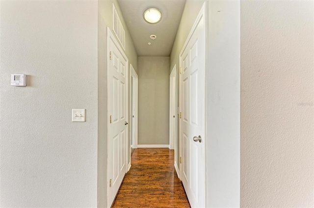 hallway featuring dark wood-type flooring and visible vents