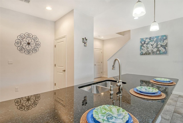 kitchen featuring sink, dark stone countertops, hanging light fixtures, and light tile patterned floors