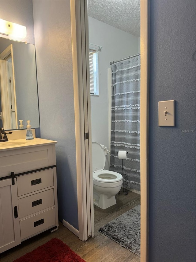 bathroom featuring a shower with curtain, toilet, vanity, hardwood / wood-style floors, and a textured ceiling