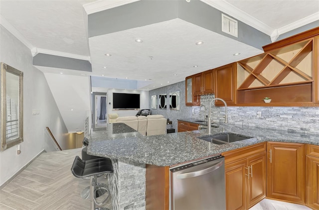 kitchen featuring a breakfast bar area, a sink, visible vents, stainless steel dishwasher, and dark stone counters